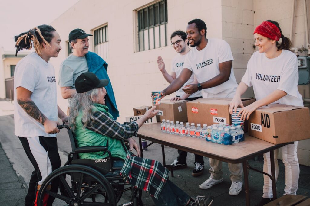 Accueil Volunteers distribute bottled water and supplies to diverse individuals in an outdoor setting, showcasing community support.