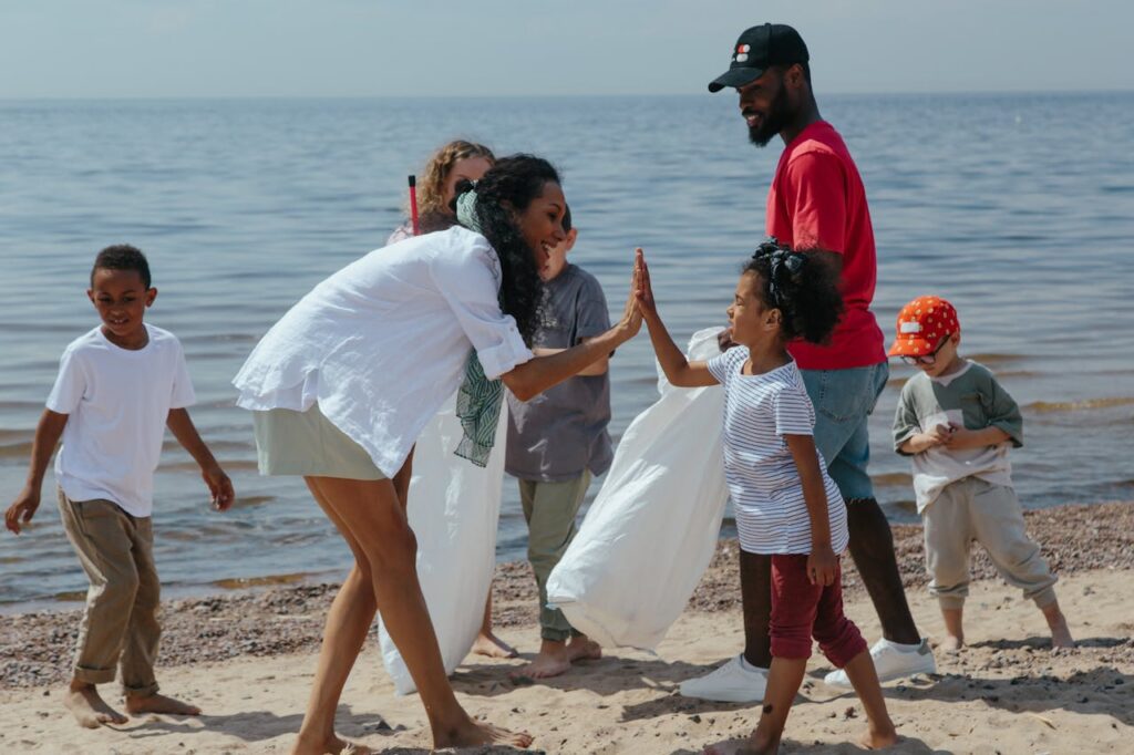 Services A diverse group of volunteers, including children and adults, clean up a beach and celebrate with high-fives.